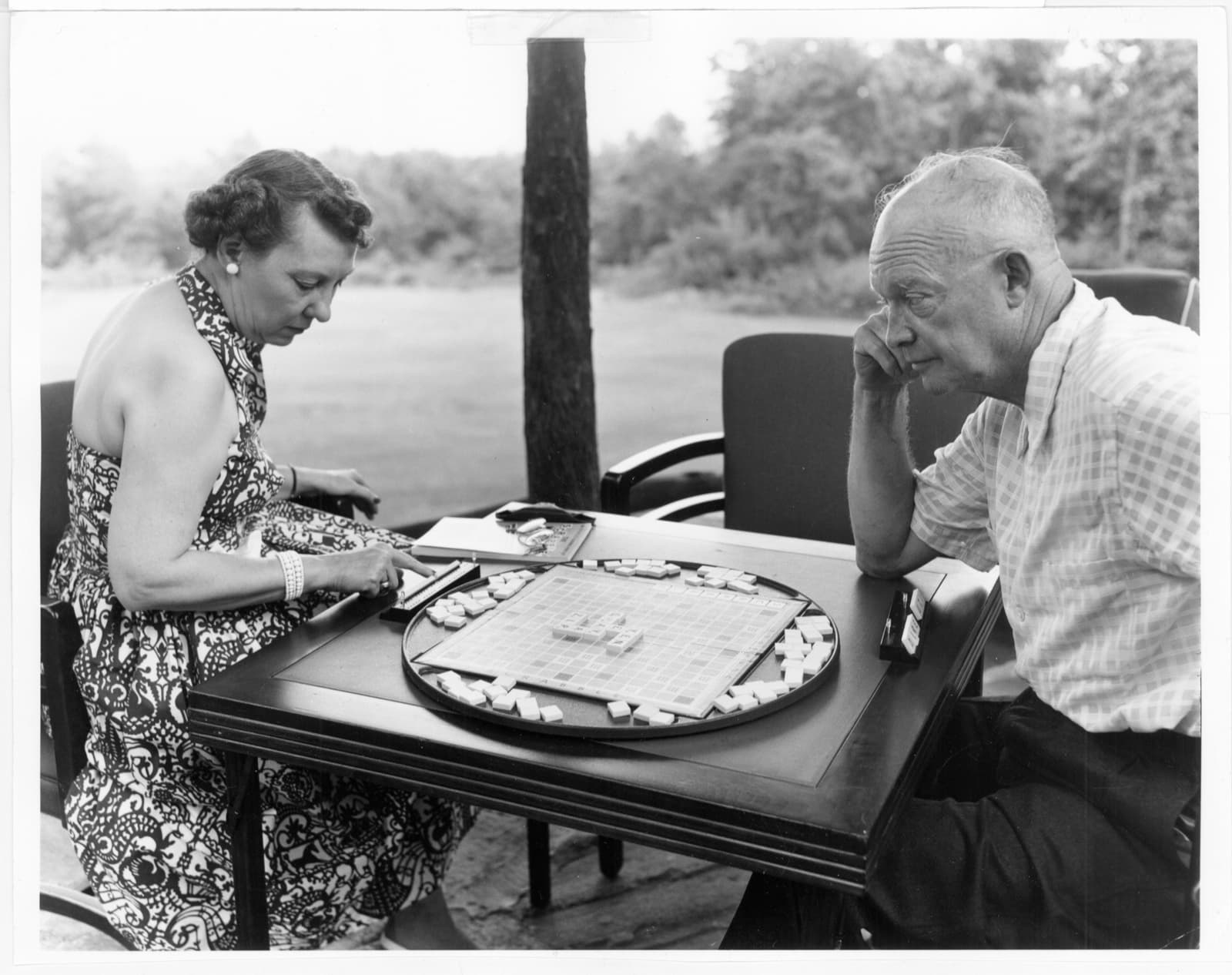 Dwight and Mamie Eisenhower playing Scrabble at a small table outdoors at Camp David